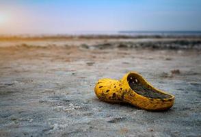 Sehr schmutziger gelber Schuh am Ufer eines Salzsees an einem sonnigen Tag. foto