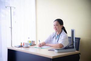 Ärztin mit medizinischen Geräten überprüft die Gesundheit des Patienten und nimmt das Weißbuch im Krankenhaus zur Kenntnis, das das Gesundheitsgeschäft ist foto