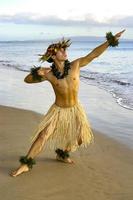 männliche Hula-Tänzerin, die am Strand neben dem Wasserrand auftritt. foto