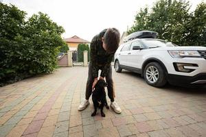 Junge spielt mit seinem Hund im Hof des Hauses, in der Nähe des Familienautos. foto