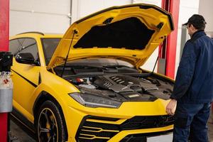 Mechaniker offene Motorhaube des gelben Sportwagen-Geländewagens. foto