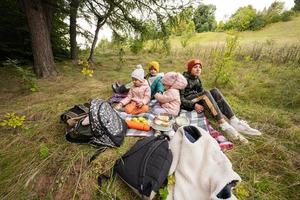 Picknick im Herbstpark. Vier Kinder essen im Wald, während sie auf einer Decke sitzen. foto