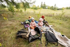 Picknick im Herbstpark. Vier Kinder essen im Wald, während sie auf einer Decke sitzen. foto