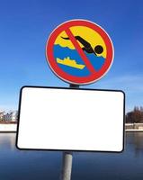 Das Schild, das das Schwimmen im schiffbaren Fluss verbietet, mit einer leeren weißen Plakette für Text. sonniger wintertag, blauer himmel.