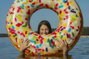 süßes jugendlich Mädchen mit buntem aufblasbarem Schwimmkreis schwimmt an einem heißen sonnigen Tag im blauen Wasser des Meeres foto