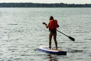 eine junge mutter schwimmt auf einem stehenden paddelbrett. Sup-Board. Wassersport foto