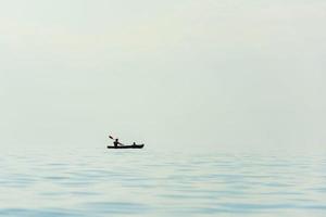 vater und kinder fahren an einem heißen sonnigen tag ein boot mit einem paddel auf dem meer, see, fluss, kanu foto