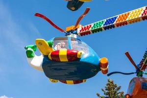 Kinderkarussells Hubschrauber in einem Vergnügungspark, Karussells und Menschen im Sommer in der Stadt foto