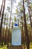 Auf einem Baumstumpf im Wald steht eine große Flasche frisches, sauberes Trinkwasser foto