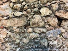 hintergrund, textur, steinmauer aus runden steinen kopfsteinpflaster ziegel natürliche oberfläche natürliche scharfe konvexe raue steinpflastersteine mit rissen foto