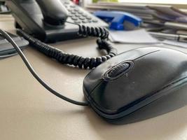 Schwarzes Festnetztelefon mit Röhre, Tasten und Kabel auf dem Arbeitstisch am Schreibtisch mit Büromaterial. geschäftliche Arbeit foto