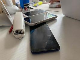 Zwei funktionierende Touchscreen-Handys, Smartphones liegen mit Schreibwaren, einem Hefter, einem Siegel und einem Laptop auf dem Tisch im Büro foto