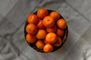 Korb mit Mandarinen- oder Orangenfrucht auf einem grauen karierten Hintergrund. foto