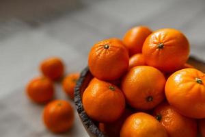Korb mit Mandarinen- oder Orangenfrucht auf einem grauen karierten Hintergrund. foto