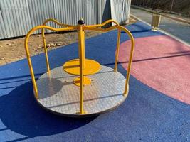 Kinder rundes blaues Schaukelkarussell aus Metall für Sportspiele im Innenhof eines neuen Gebäudes auf einem Kinderspielplatz foto