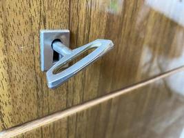 Eisen-Metall-Chrom-Schlüssel zum Öffnen und Schließen des Schlosses im Schlüsselloch an einer Holztür foto