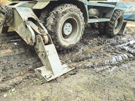 ein Traktor mit großen, schwarzen Rädern im Schlamm. Metallanker, um die Maschine an Ort und Stelle zu halten. Schwarzes Rad steckt in einer Schlammpfütze fest foto