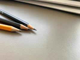 Auf dem Arbeitstisch im Büro liegen drei spitze Bleistifte neben Ordnern mit Blättern und Dokumenten. Schreibwaren foto