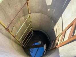 Ein großer runder Tiefbrunnen aus Betonringen mit sauberem Grundwasser zum Trinken mit alten rostigen Treppen foto