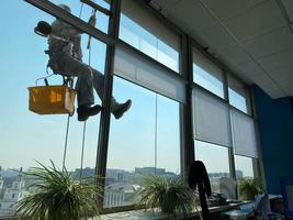 Fensterputzer an der Hochhausfassade. Arbeiter wäscht das Fenster an der Wolkenkratzerwand foto