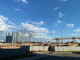 Turmdrehkrane beim Bau eines neuen Wohngebäudes. Baustelle und Hochhaus gegen blauen Himmel. Konstruktion foto