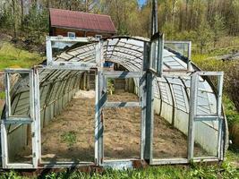 hausgemachtes Gewächshaus aus alten Fenstern mit Glas für den Anbau von frischem Gemüse auf dem Land foto