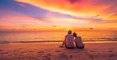 liebespaar, das zusammen sonnenuntergang auf strandreisesommerferien beobachtet. leute silhouette von hinten sitzen genießen blick sonnenuntergang meer tropische insel, urlaubsziel. romantischer freiheitslebensstil foto