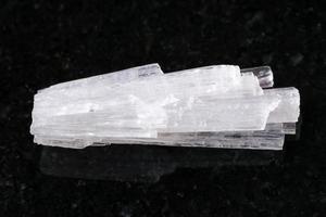 roher kristall aus skolezit-edelstein auf dunkel foto