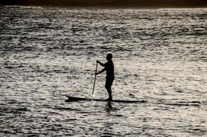 Silhouette eines Mannes im Paddelbrett foto