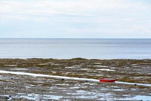 Rotes Boot auf der Gaspesie-Halbinsel in Kanada zwischen dem Meer und wunderschönen Landschaften an einem Sommertag foto