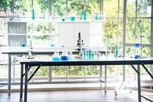Vorbereitung von Laborgeräten wie Glaswaren, Röhrchen mit blauer Flüssigkeit auf dem weißen Tisch. Das Chemieexperiment in der wissenschaftlichen Forschung foto