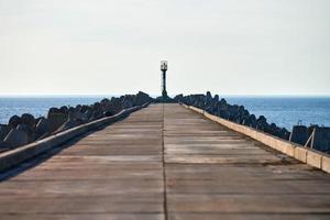 leerer langer betonpier mit wellenbrechern und signalleuchtturm im europäischen hafen, kopierraum foto