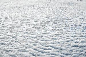 atemberaubender blick über die wolken aus dem flugzeugfenster, dicke weiße blaue wolken sehen aus wie weicher schaum foto