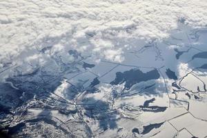 luftwolkengebilde blick über die wolkenspitze zu schneebedeckten flüssen, straßen, städten und feldern, winterluft foto