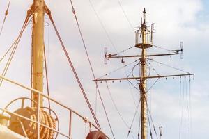 Schiffsmast einer Fregatte, eines Langboots oder eines Marineschlachtschiffs. Mastmast aus Metall. Schiff erwartet den Kapitän an den Docks. gesenkte Segel, blauer Himmel im Hintergrund. foto