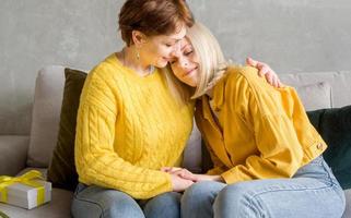 mutter umarmt ihre erwachsene tochter, während sie auf der couch sitzt. familiäre Beziehungen foto