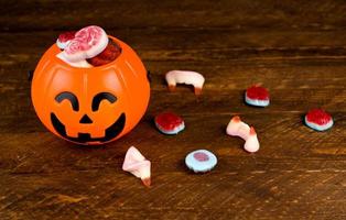 Draufsicht auf Gelee-Halloween-Bonbons in der Nähe einer kürbisförmigen Schüssel. Gehirne, Schädel usw. Süßes oder Saures foto