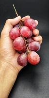 rote Traubenfrüchte, die sich über der Hand befinden foto