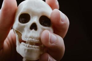 Menschliches Skelettschädelmodell in der Hand, das für die medizinische Anatomiewissenschaft posiert