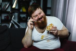 Mann isst, während er am Telefon spricht foto