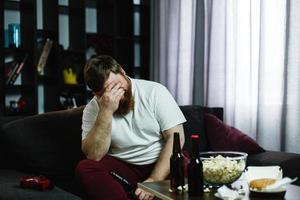 trauriger dicker Mann sitzt auf dem Sofa foto