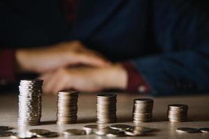 geld sparen hand, die münzen auf tisch mit sonnenschein stapeln. Konzept Finanzen und Rechnungswesen foto