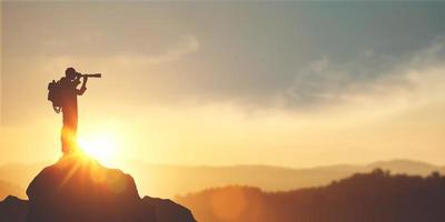 Vision für Erfolgsideen. Unternehmerperspektive für die Zukunftsplanung. Silhouette eines Mannes, der ein Fernglas auf dem Berggipfel vor hellem Sonnenlichthimmelhintergrund hält. foto