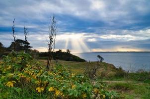 an der Küste von Hundested. Sonnenstrahlen brechen durch die Wolken durch den dramatischen Himmel foto