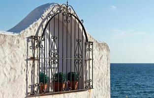 Fenster mit Töpfen und schmiedeeisernem Zaun mit Blick auf das Meer. horizontales Bild. foto