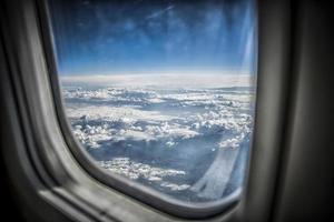 Blick auf blauen Himmel und flauschige Wolken aus einem Flugzeugfenster foto