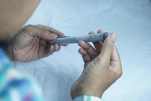 teilweise verschwommenes Bild eines Mannes mit Insulinstift. medizinische Geräte sind einfach zur Selbstinjektion foto