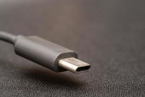 nahaufnahme des usb-typ-c-steckers mit einem grauen kabel auf dunklem hintergrund. seitliches Nahaufnahmefoto des grauen Typ-C-Kabels. foto