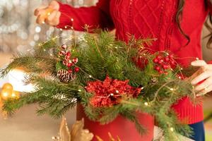 Mädchen sammelt einen Weihnachtsstrauß aus Tannenzweigen, Blumen und Christbaumschmuck foto