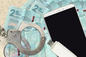 2 kolumbianische Pesos-Scheine und Smartphone mit Polizeihandschellen. Konzept von Hacker-Phishing-Angriffen, illegalem Betrug oder weicher Verteilung von Malware foto